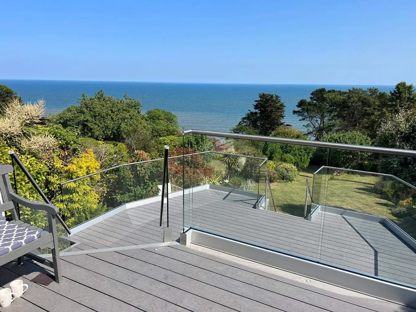 Grey composite deck with a glass balustrade overlooking a sea view