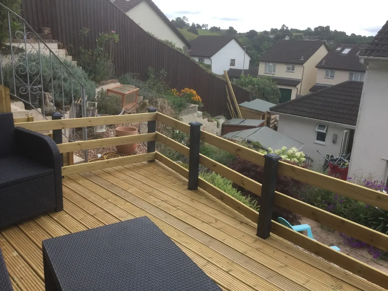 Raised timber deck with a balustrade built across a sloping garden in Devon