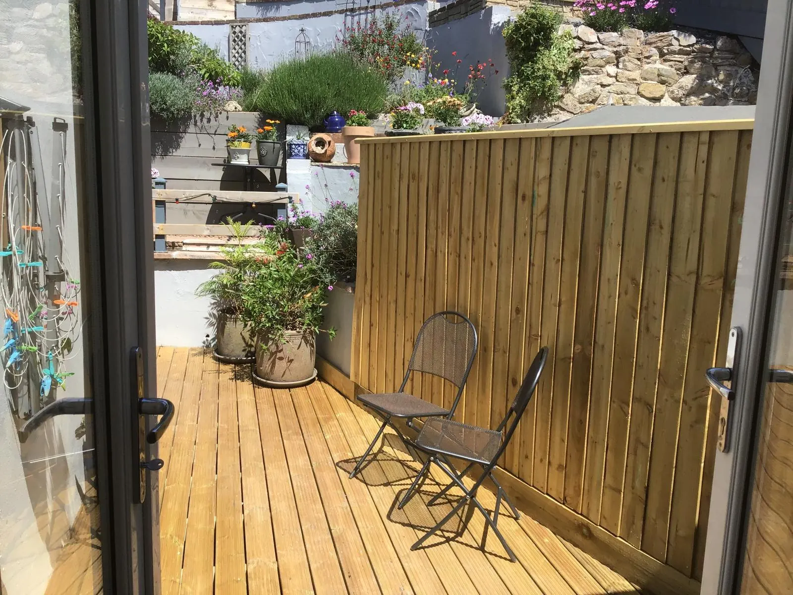 Timber courtyard deck seen from patio doors, with a close board fence along one side