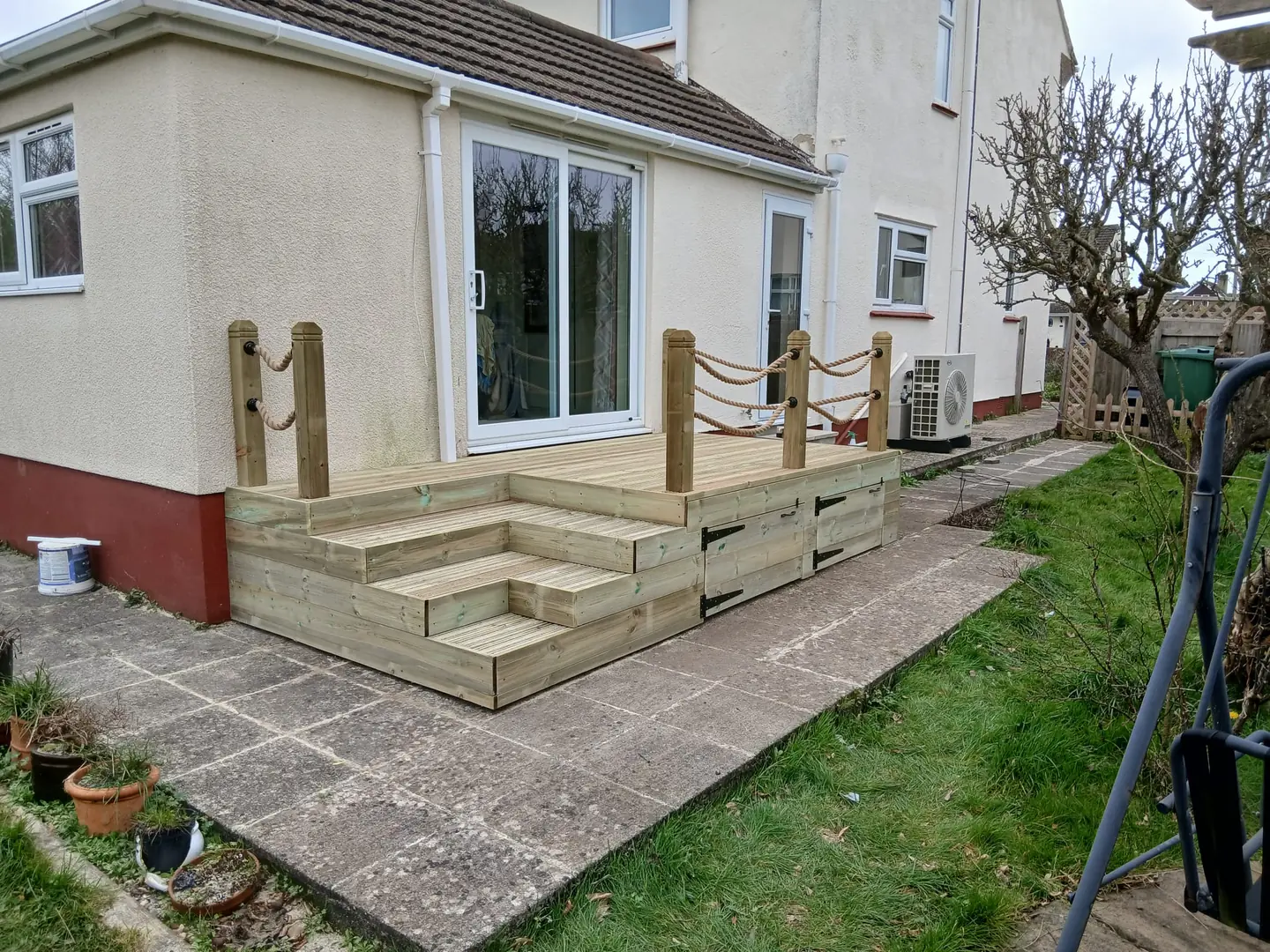 Low timber deck outside patio doors with wraparound steps and rope handrails on timber posts