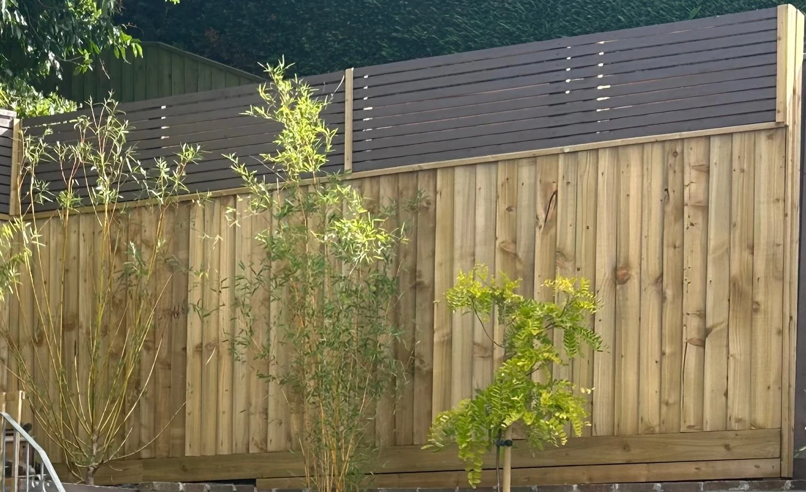 Close board fence raised with a brown horizontal slatted topper for extra privacy