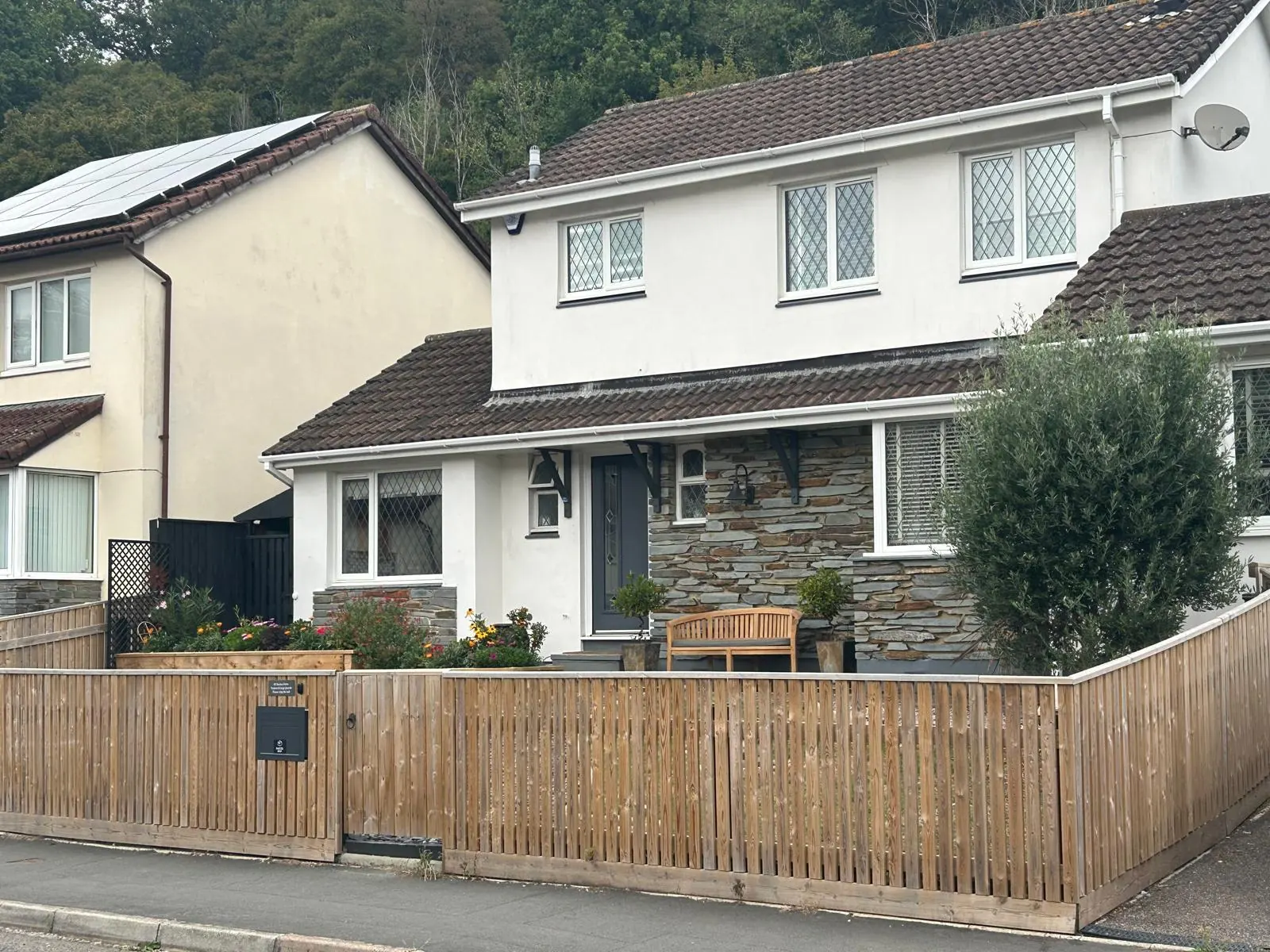 Vertical board timber fence following the slope of the pavement along a front garden boundary