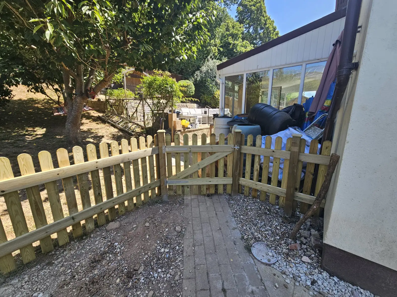 Pressure-treated round top picket fence with a ledged and braced timber garden gate on galvanised hinges